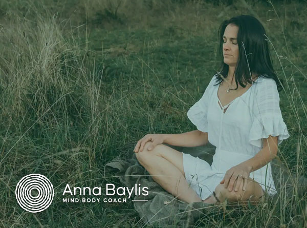 Woman wearing a white dress meditating in a field
